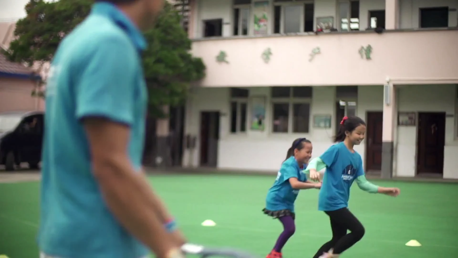 The coach leading a group activity outside the school building.
