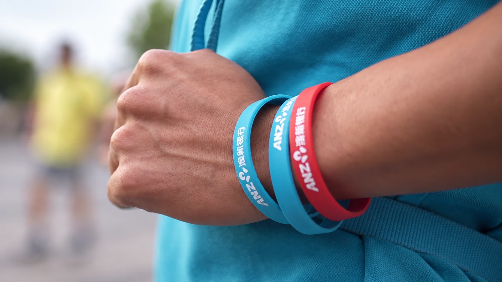 A hand holding blue and white ANZ programme wristbands.