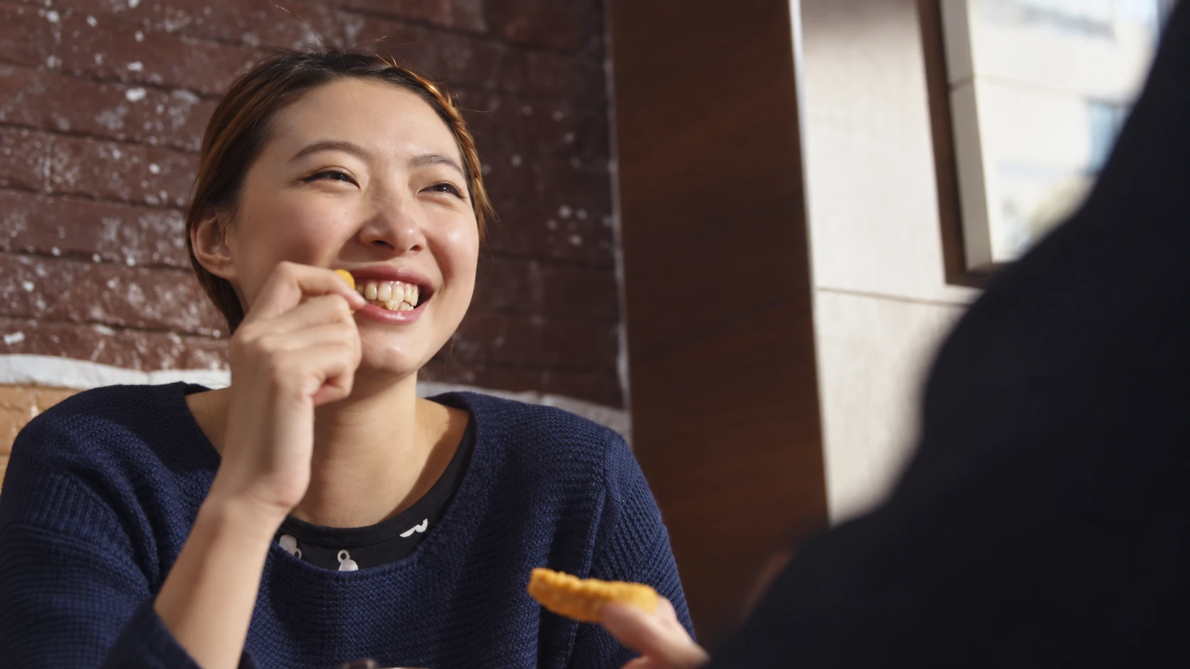 A smiling diner holding a small bite of food in the restaurant.