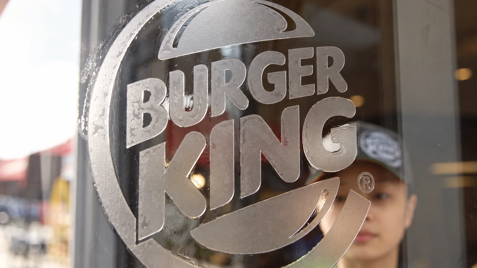 A team member cleaning glass behind a Burger King emblem.