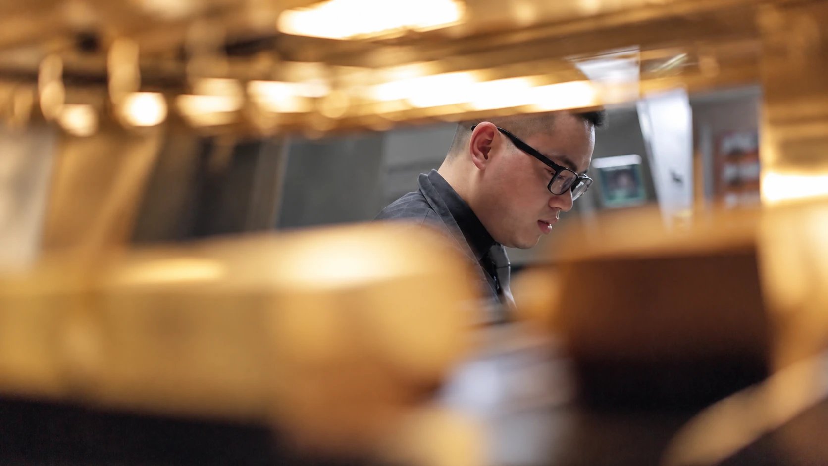 A team member seen through the softly lit kitchen pass.