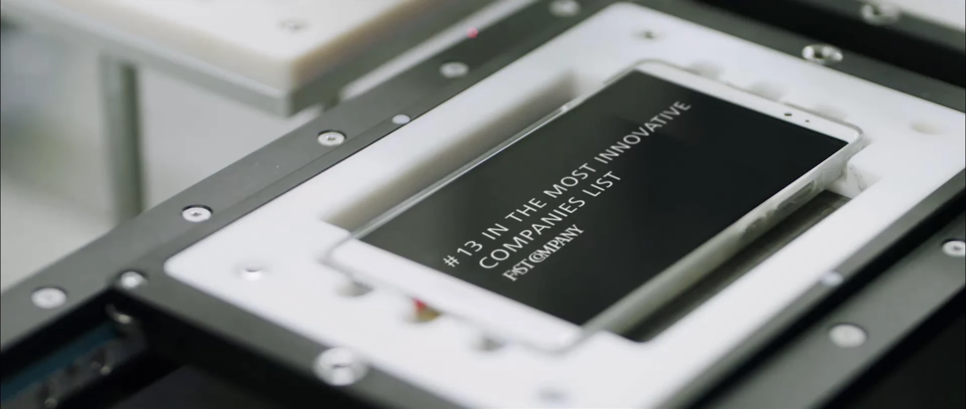 A phone held in an industrial fixture and displaying an original campaign quote.