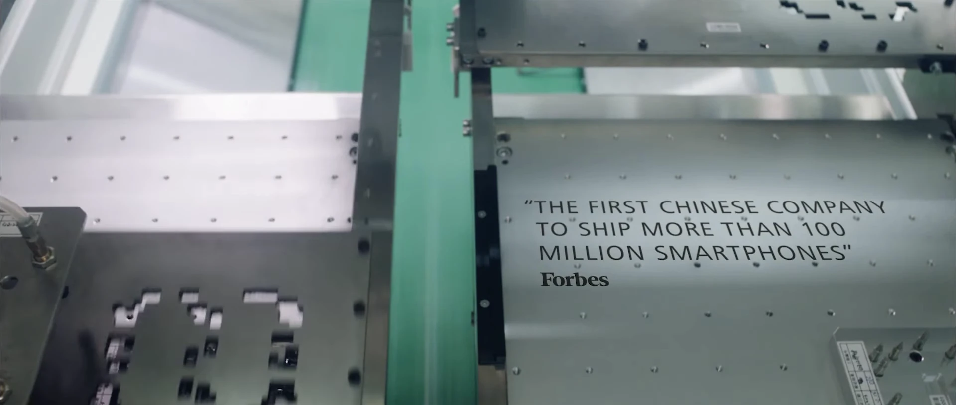 An original film frame showing a Forbes quote over a metal manufacturing fixture.