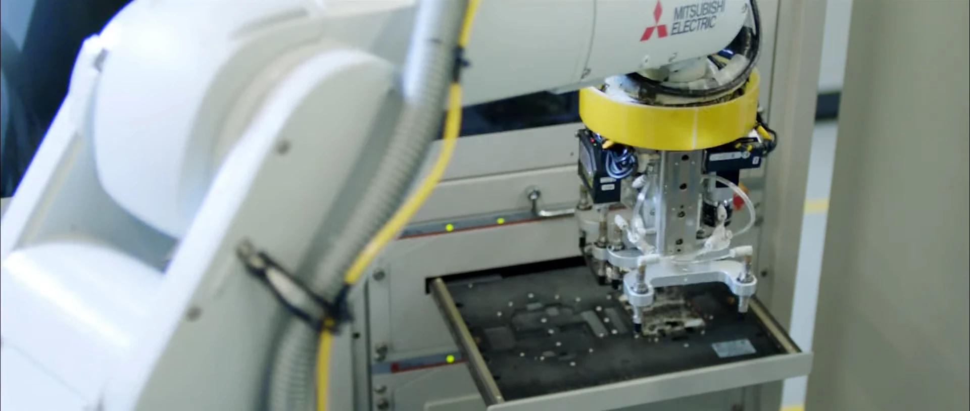 A robotic arm positioned over a smartphone in an industrial fixture.