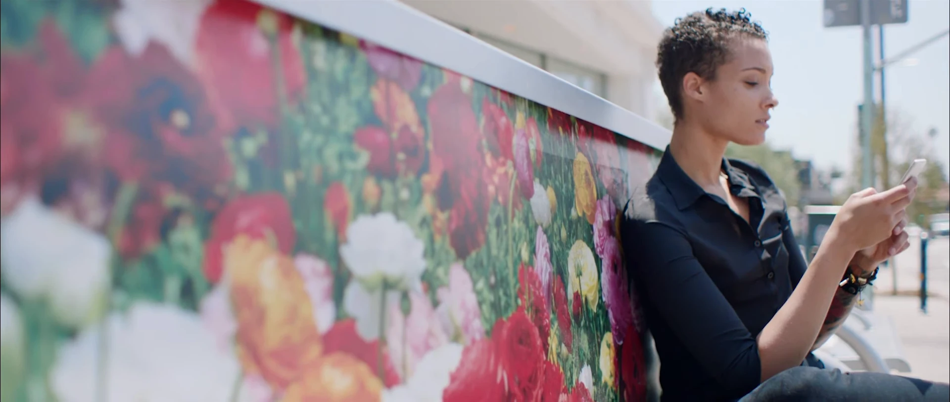 A woman using a smartphone beside a colourful painted wall.