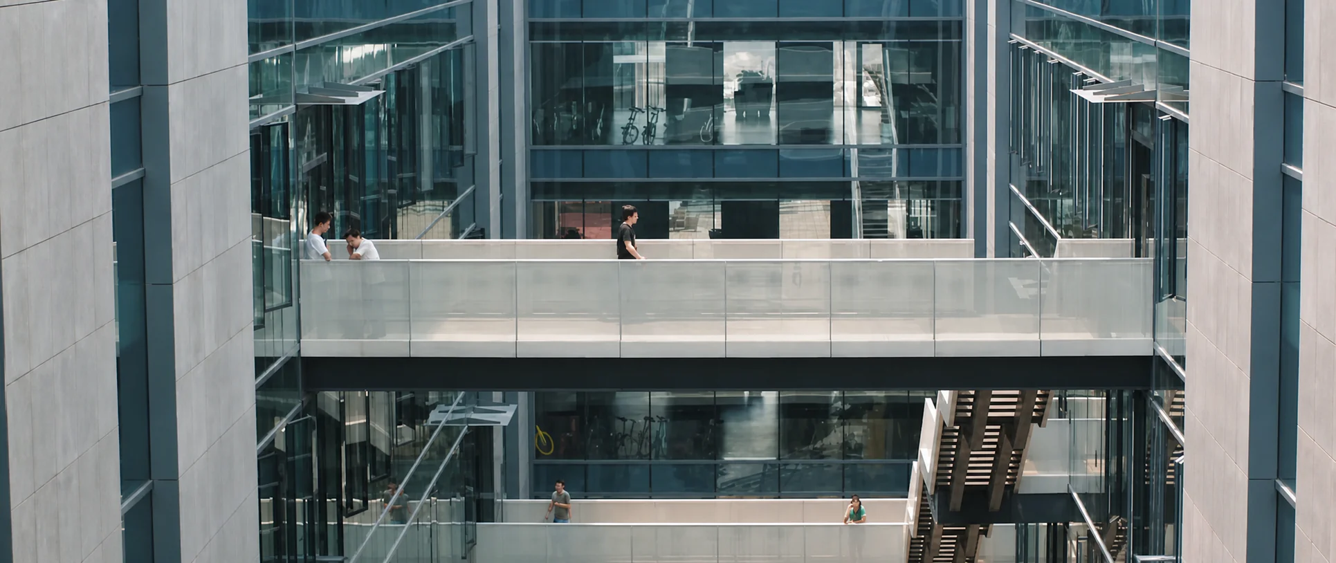 People moving through a glass office atrium.