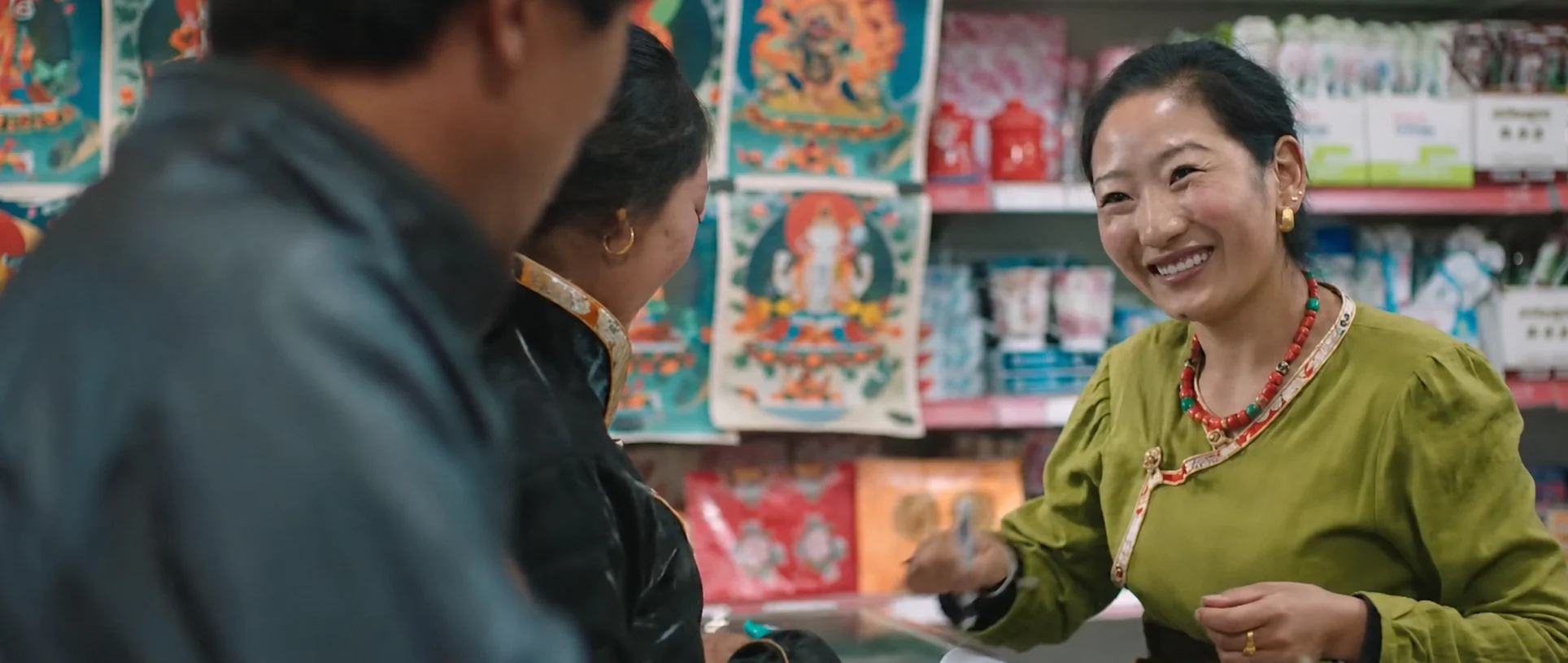 A shopkeeper speaking with visitors inside a colourful store.