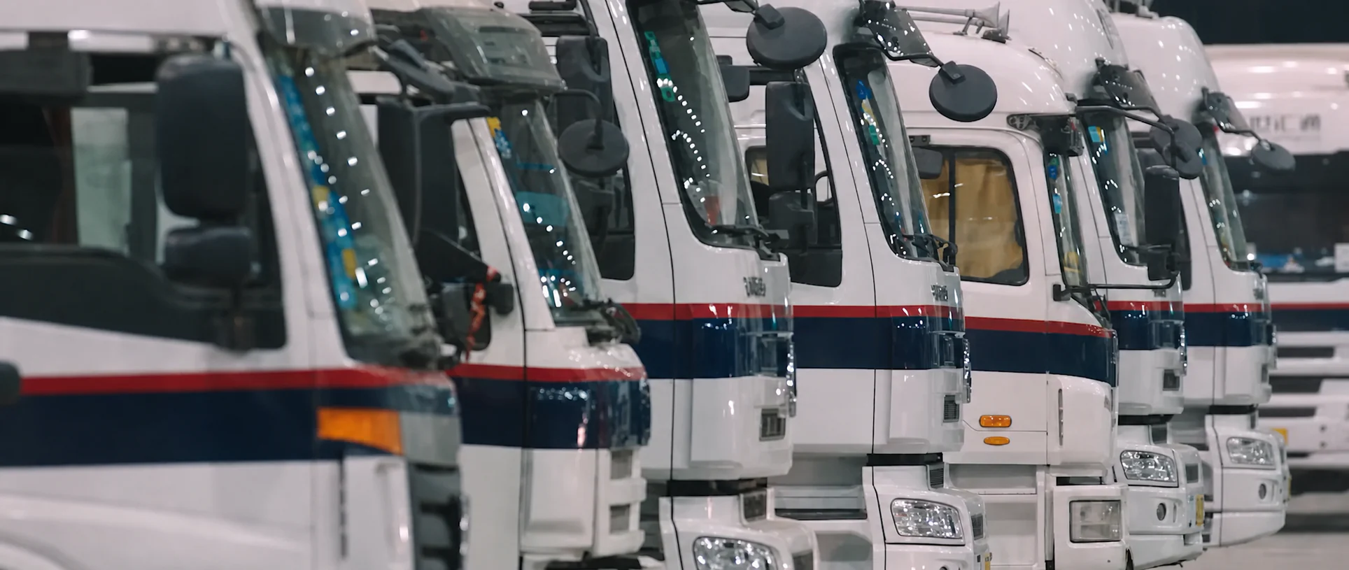 A row of delivery trucks parked inside a logistics facility.