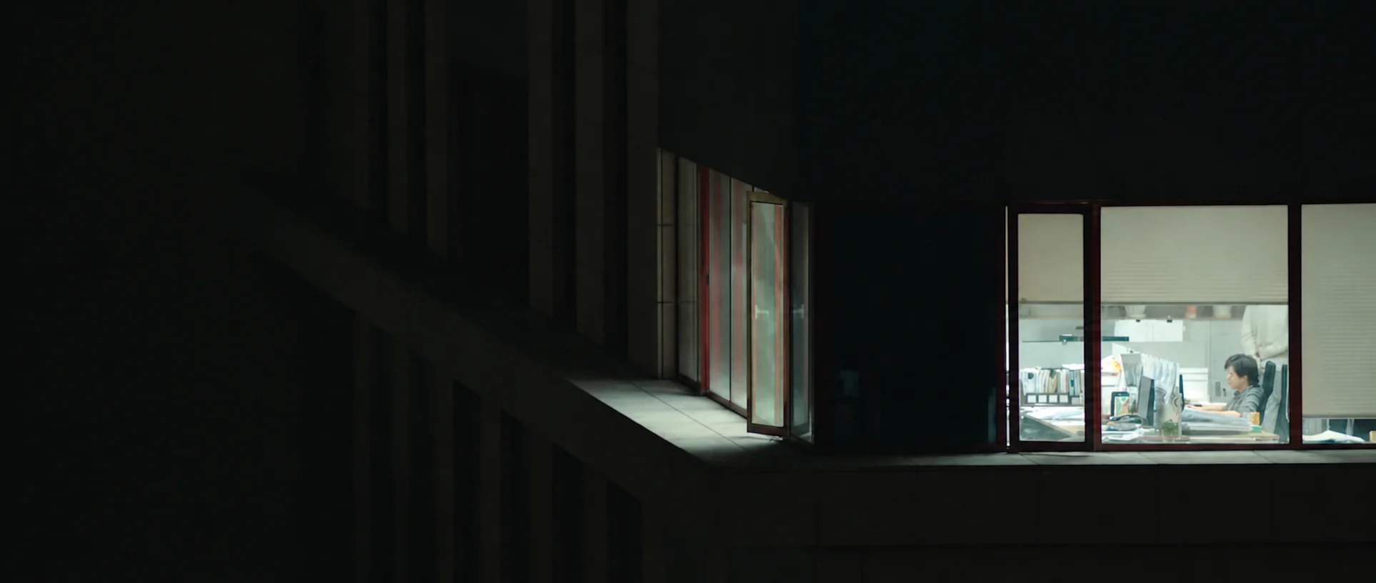 Bright workspaces visible through windows at night.