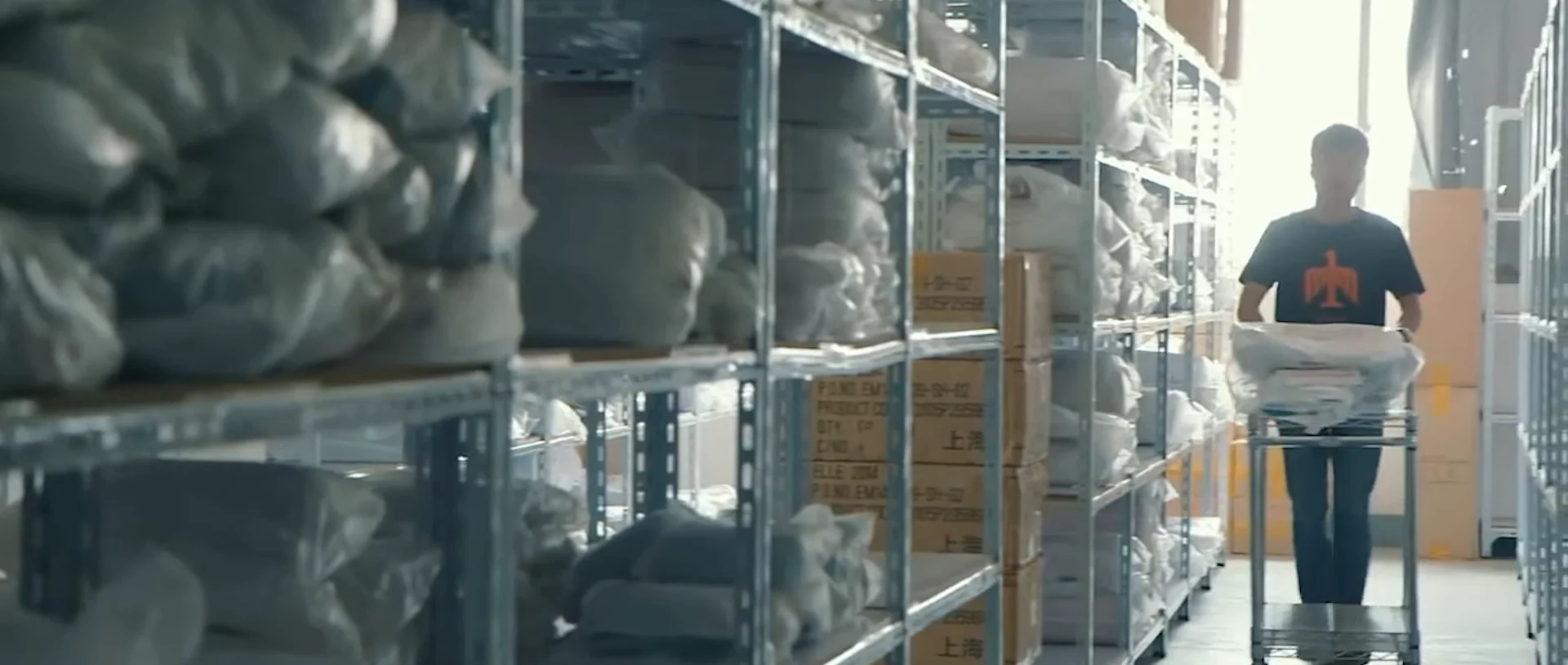 A worker moving parcels through a warehouse aisle.