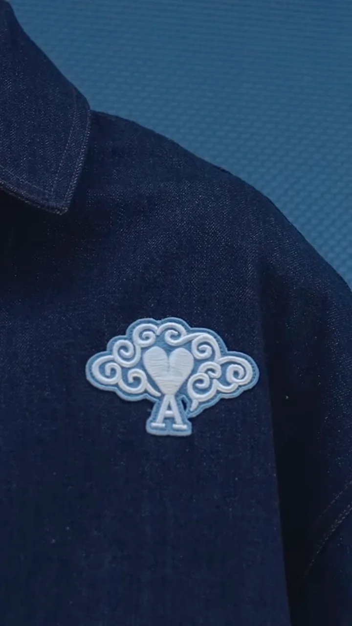 Close view of a navy jacket with a pale embroidered AMI emblem in the Guangzhou flagship film.