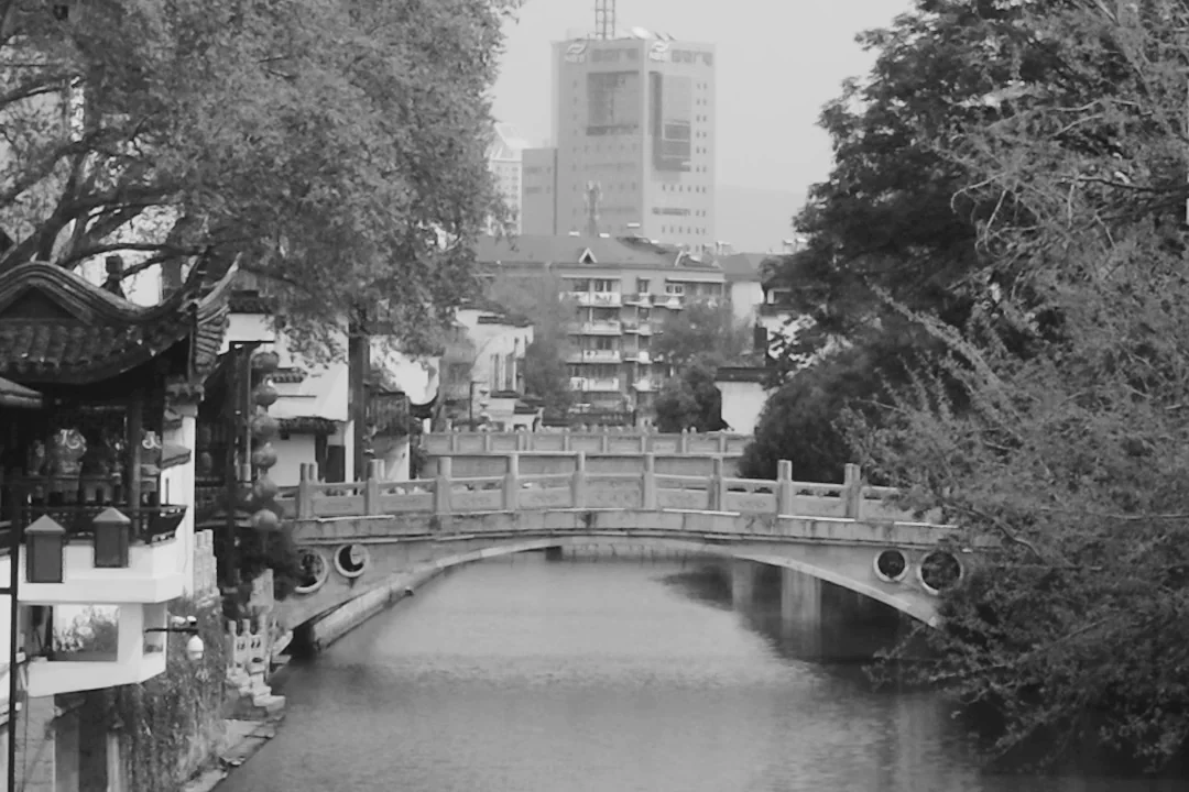 A bridge, waterway, traditional roofs and modern buildings in the Nanjing project footage.