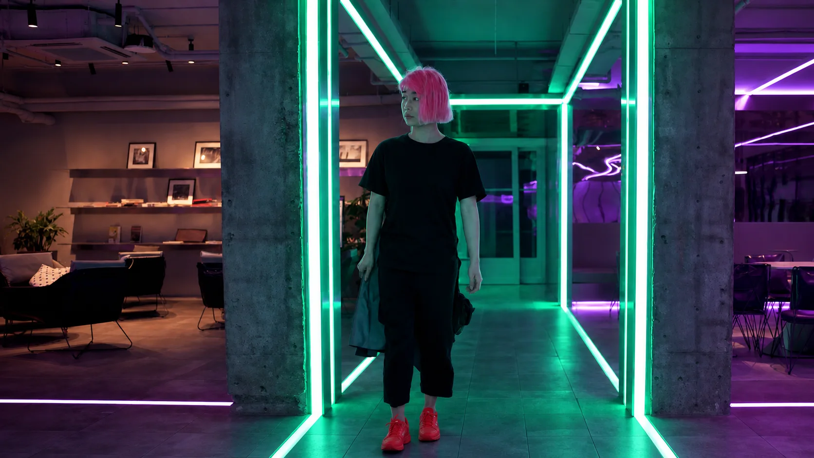 Jennifer Bin walking through a green and violet neon interior