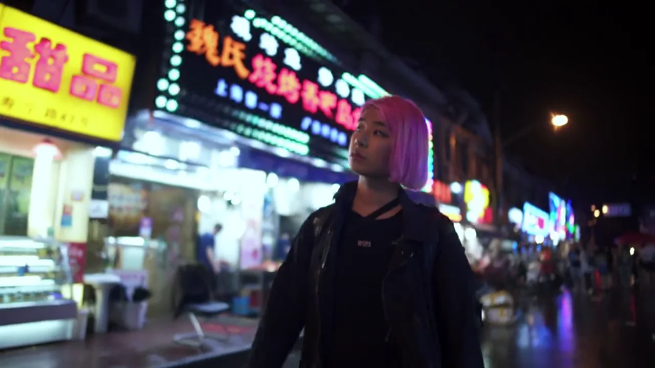 Jennifer Bin walking through a neon-lit Shanghai night market