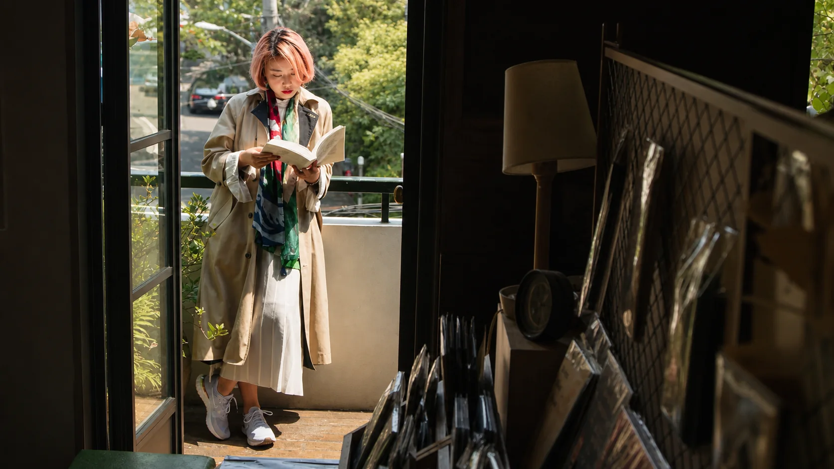 One Crew member reading a book beside a sunlit bookshop window