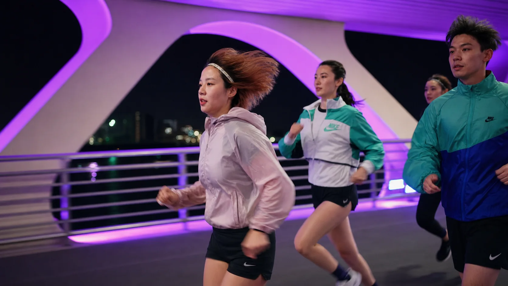 Side view of One Crew runners on a purple-lit bridge