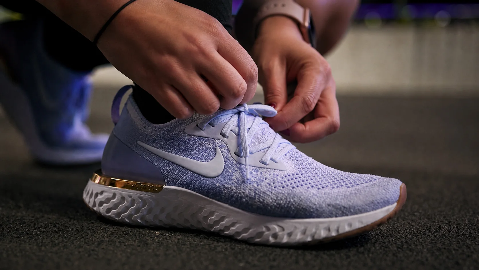 Hands tying the laces of a light blue Nike React running shoe