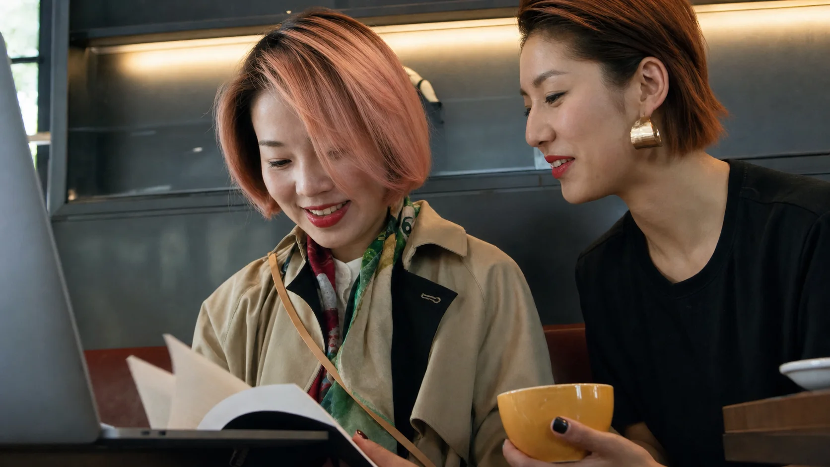 Two One Crew members looking at a laptop and booklet during cafe filming