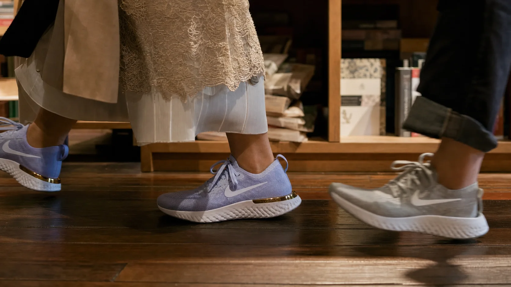 Low view of light blue Nike React shoes walking past bookshop shelves