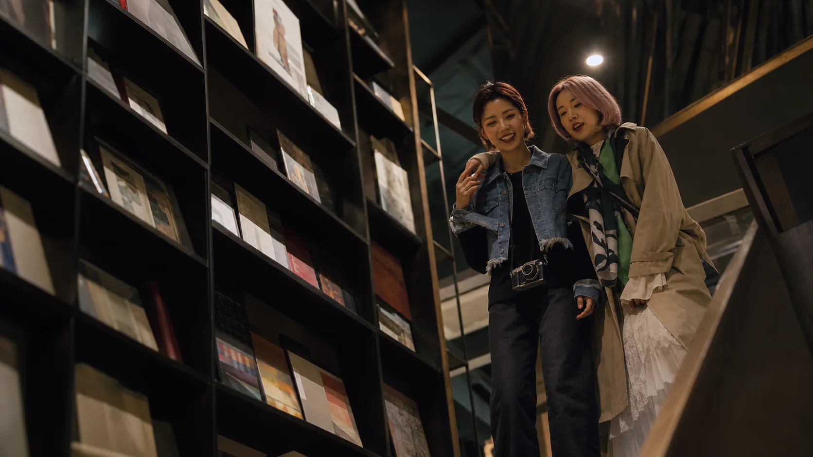 Two One Crew members standing together between tall bookshop shelves