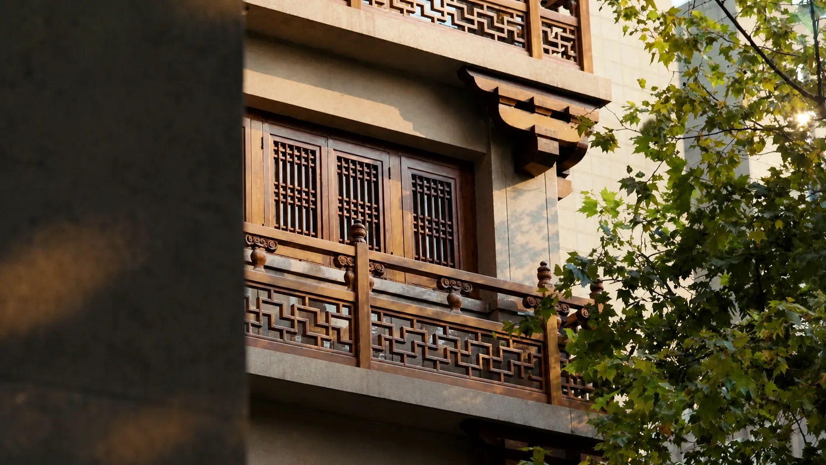 Traditional wood facade and lattice windows framed by trees in Shanghai