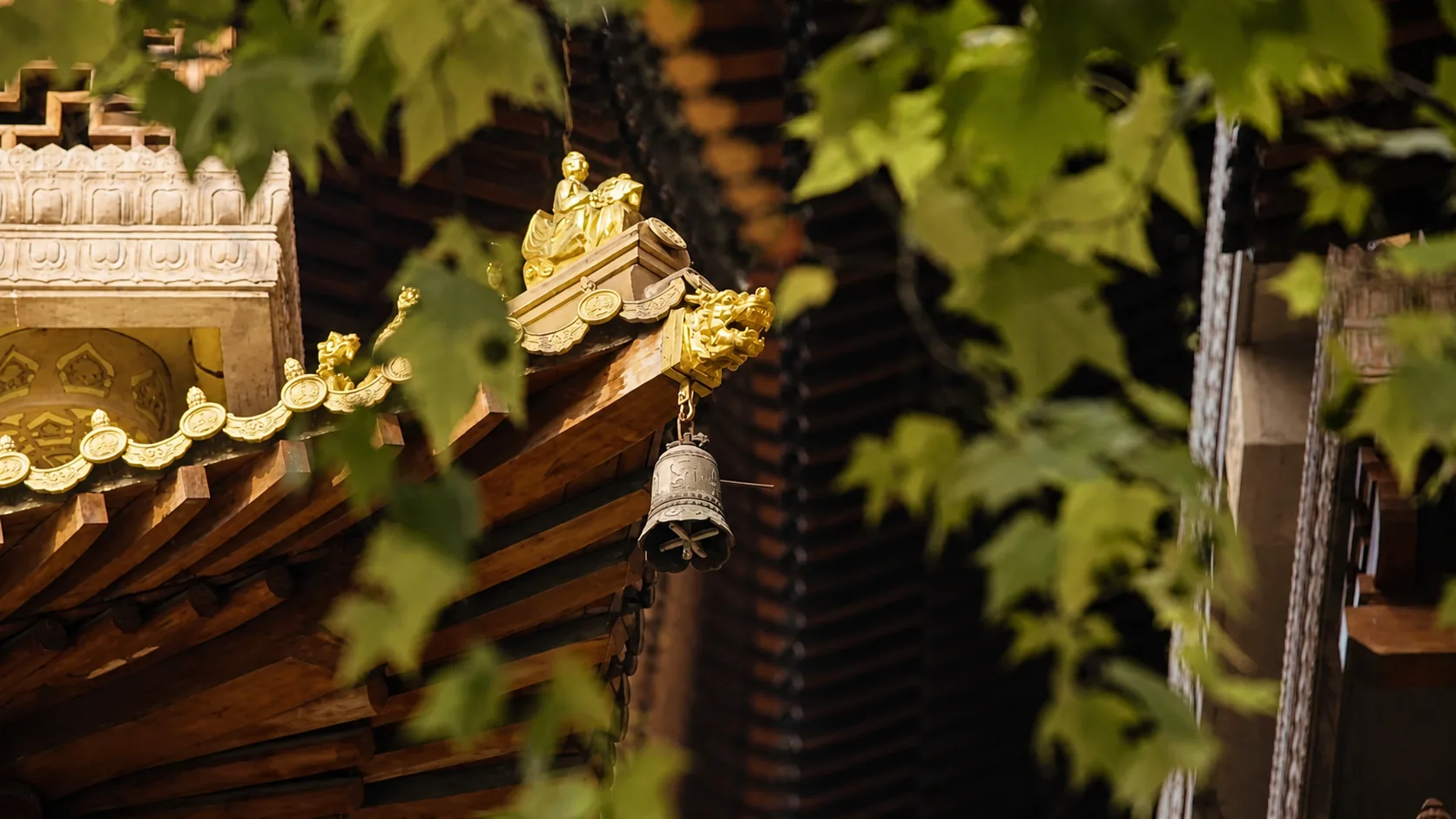 Ornate traditional roof detail with a hanging bell and foliage near Suhe Creek