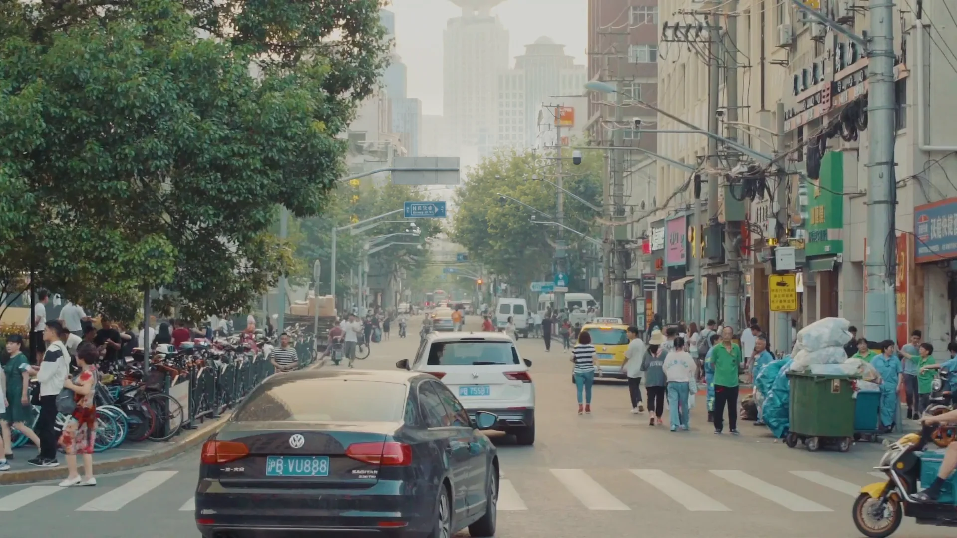 Busy Shanghai neighbourhood street with traffic, pedestrians and trees