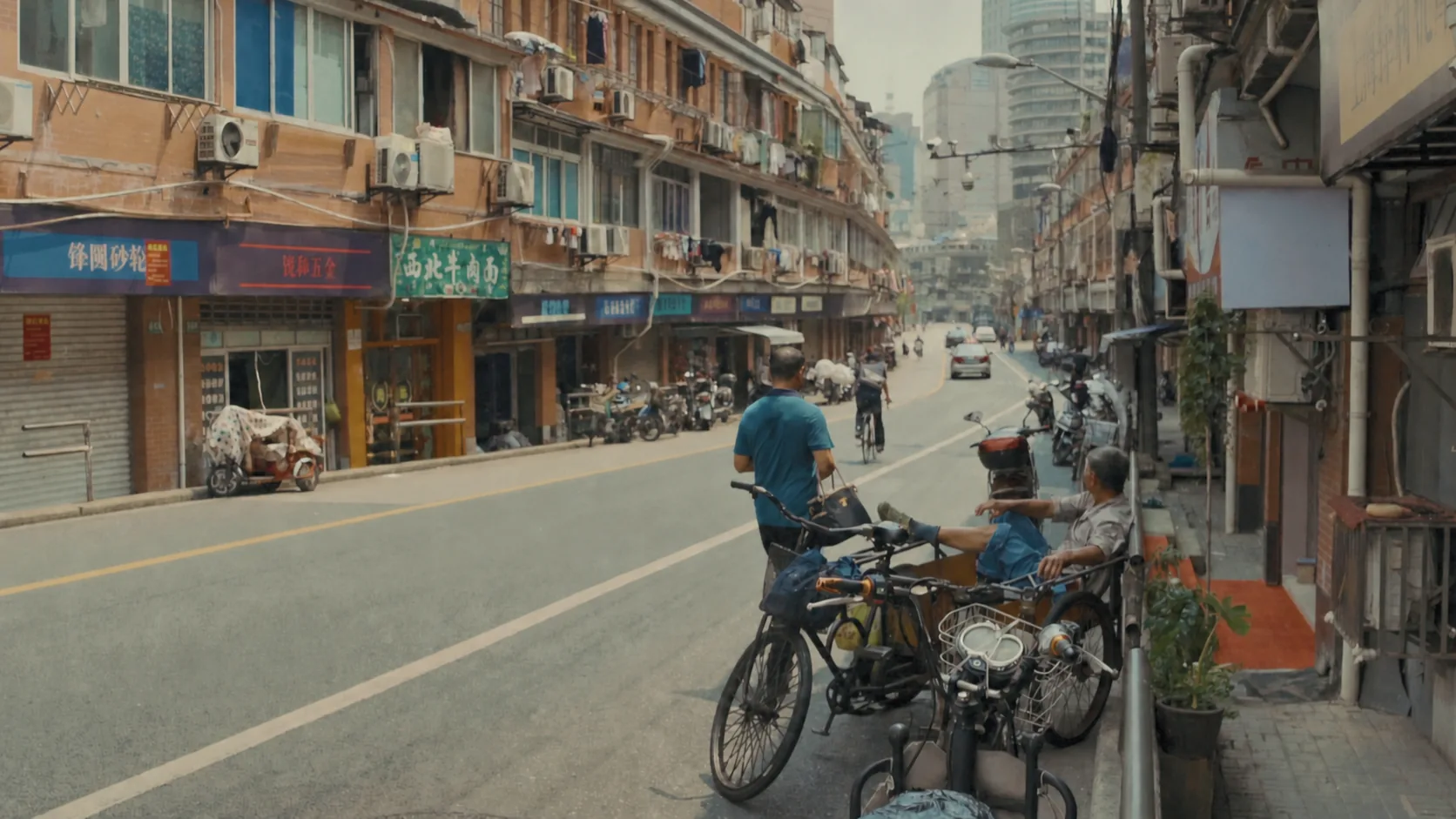 Older Shanghai street with shopfronts, bicycles, scooters and overhead wires