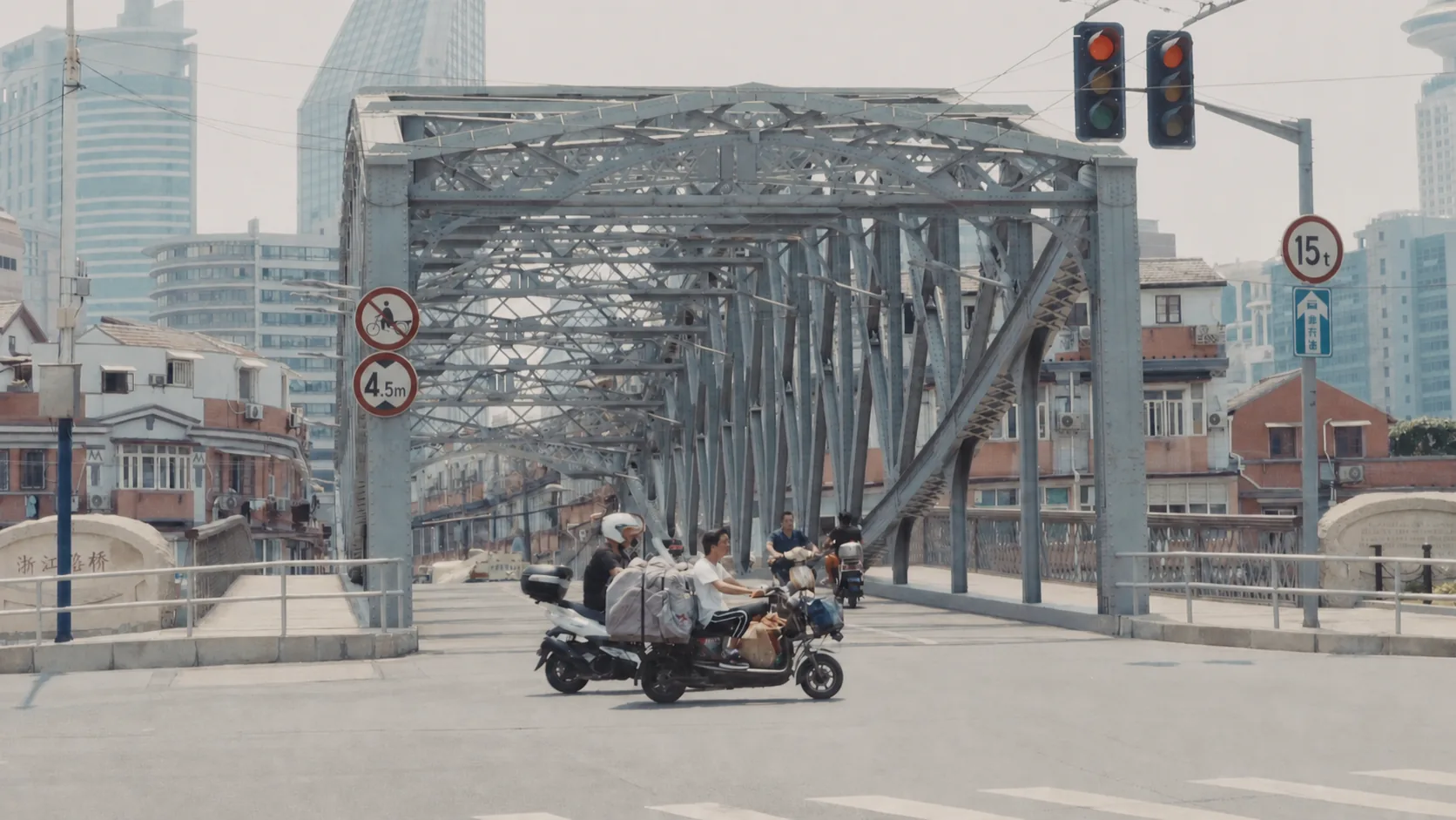 Scooters and traffic approaching a steel truss bridge in Shanghai