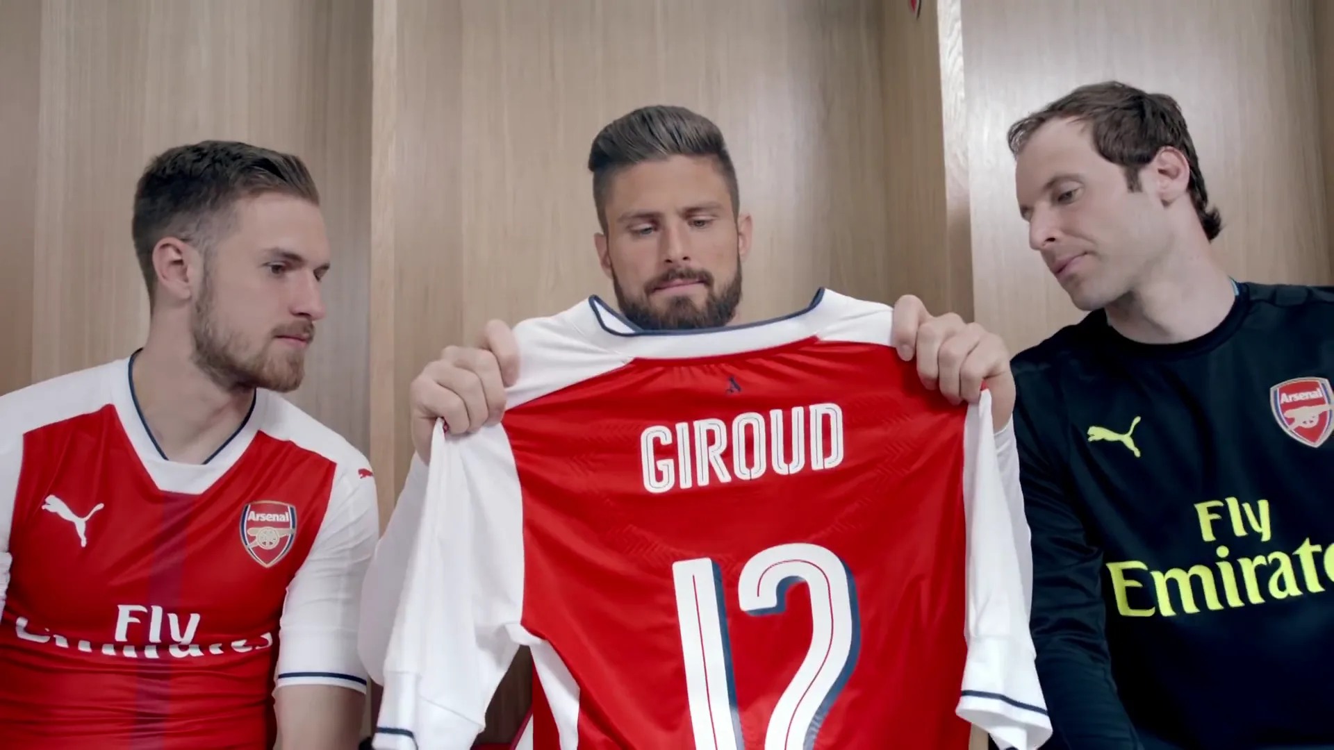 Three Arsenal players looking at a Giroud 12 shirt in incorporated campaign footage outside the Shanghai production segment