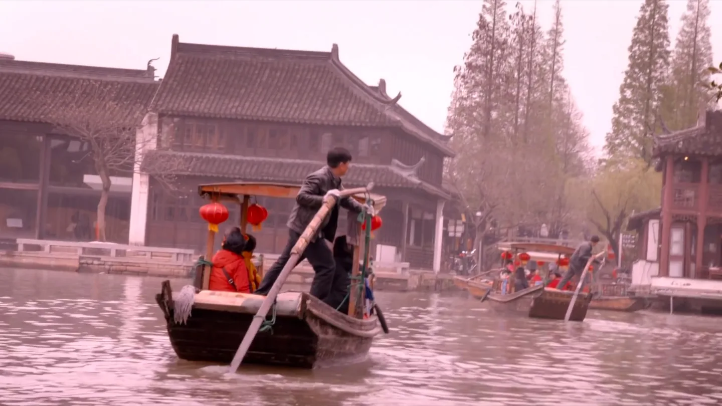 A wooden boat moving through a traditional Shanghai water town