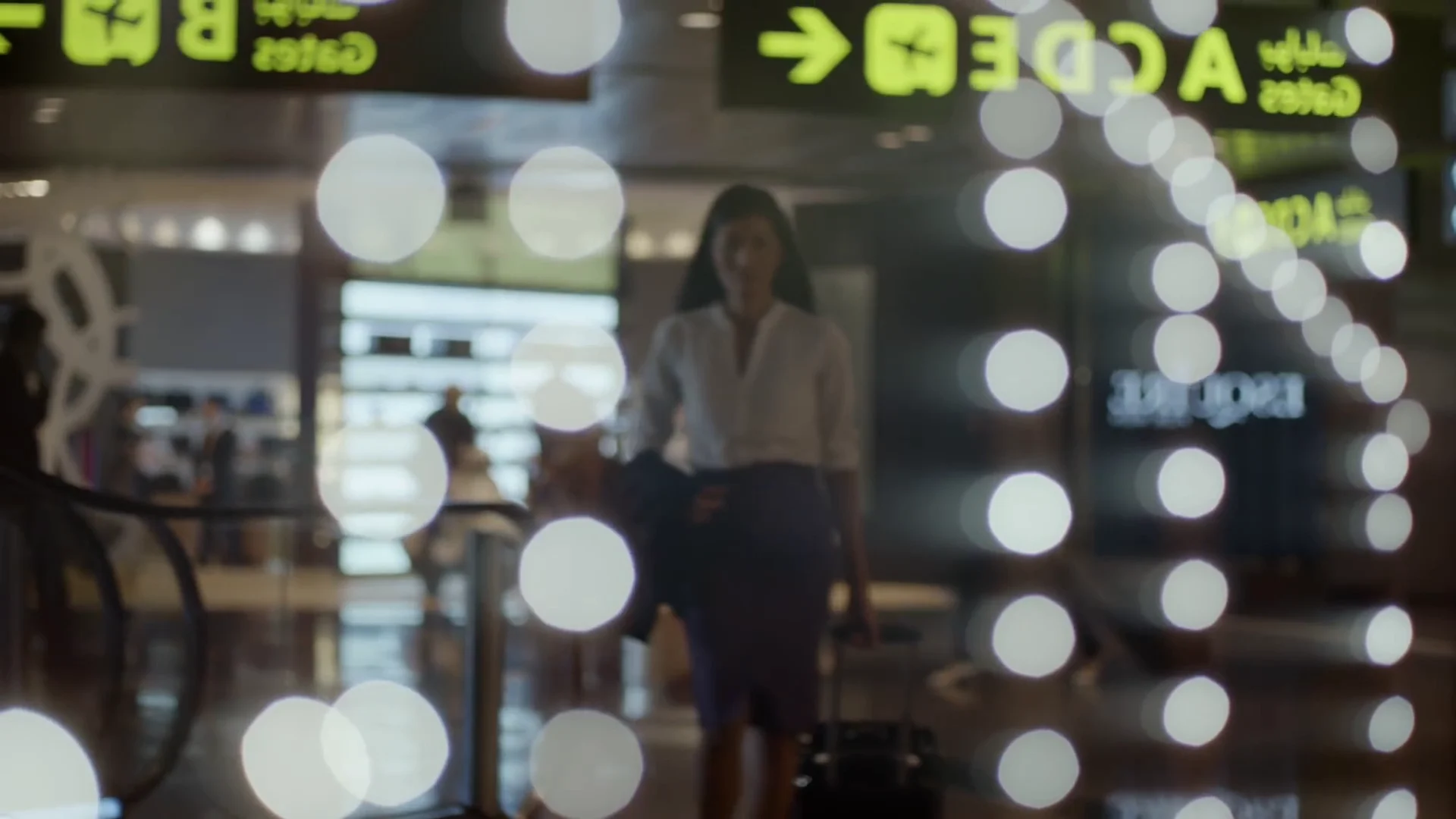 Traveller moving through an airport terminal beneath reflected gate signage