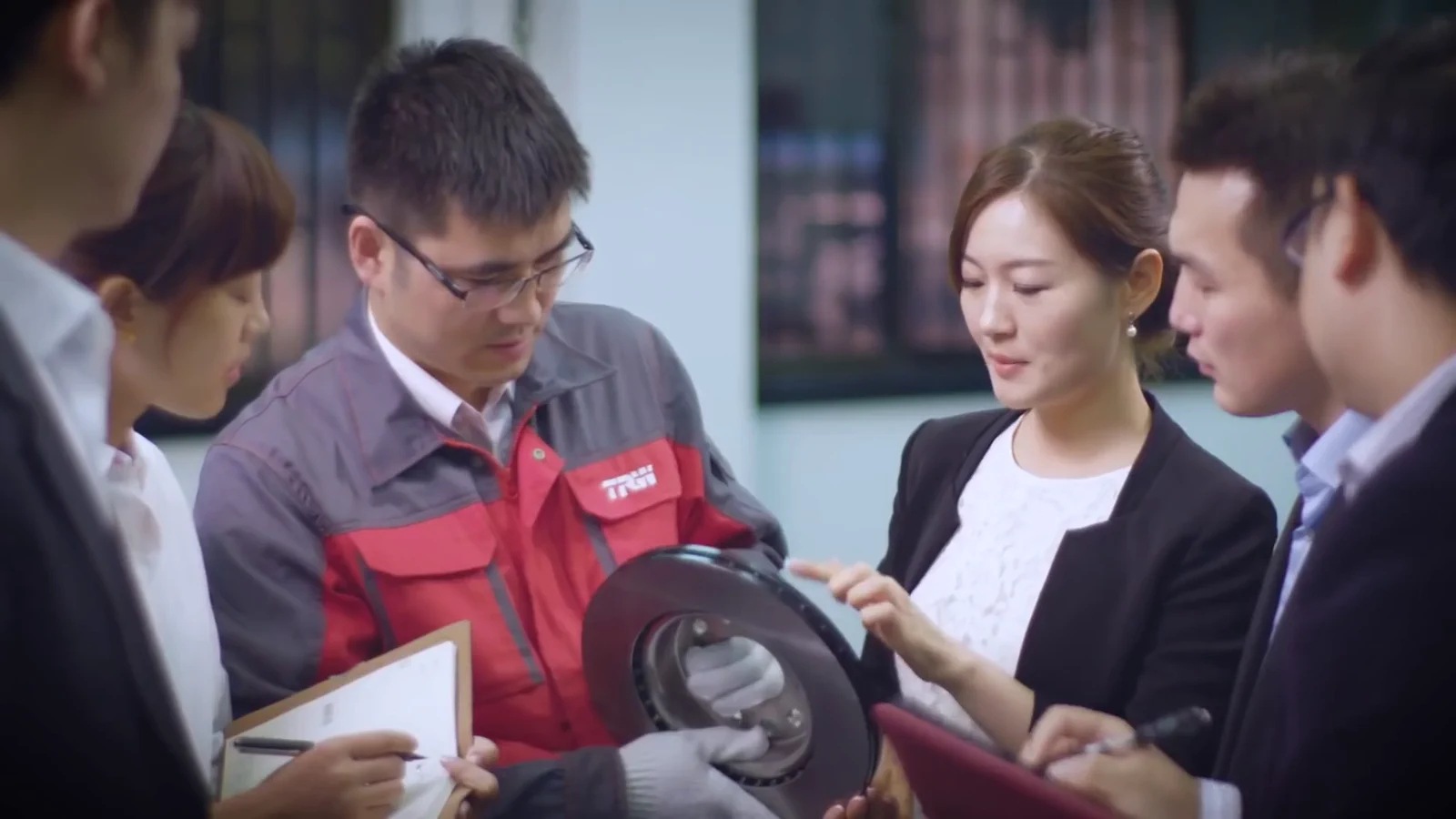 Group reviewing a brake disc while a technician holds the component
