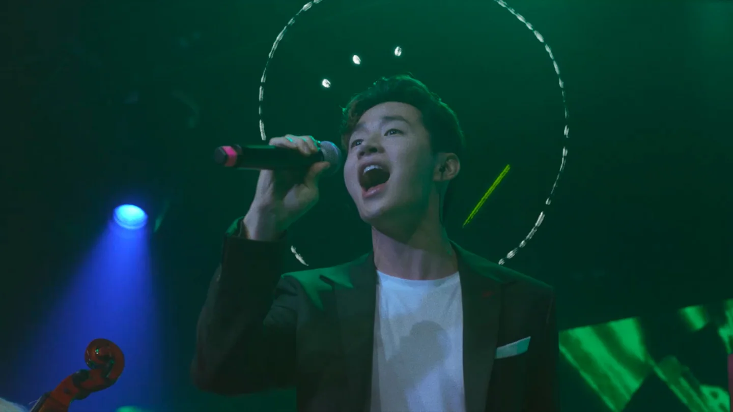 Henry Lau performs on a green and blue lit stage in Beijing