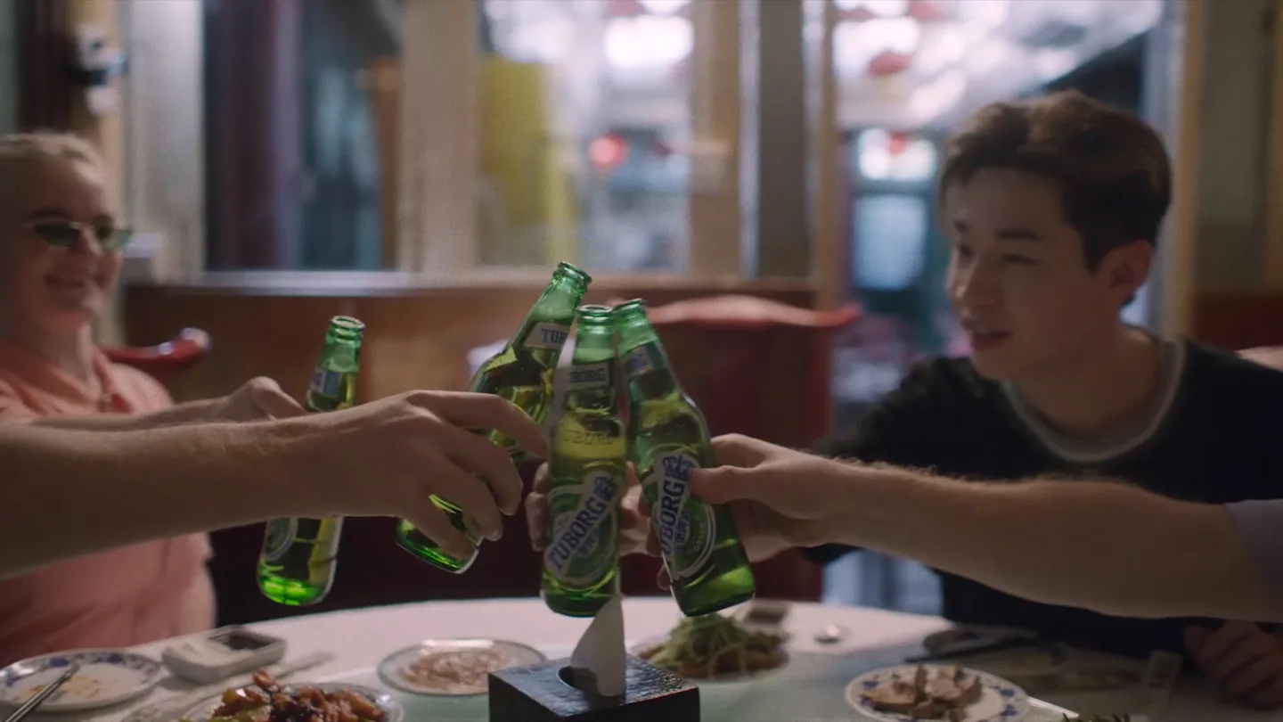 Tuborg bottles are raised during a group toast in Beijing