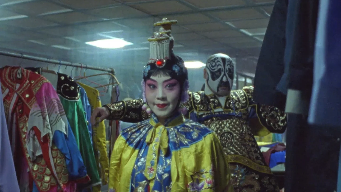 A Beijing opera performer waits backstage among costumes