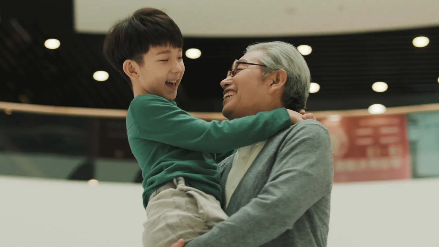 Grandfather holding his laughing grandson inside a Beijing Wanda mall