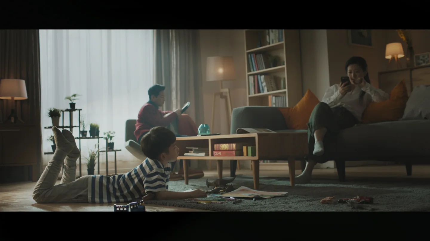 Boy lying on the floor while his parents look at separate devices at home