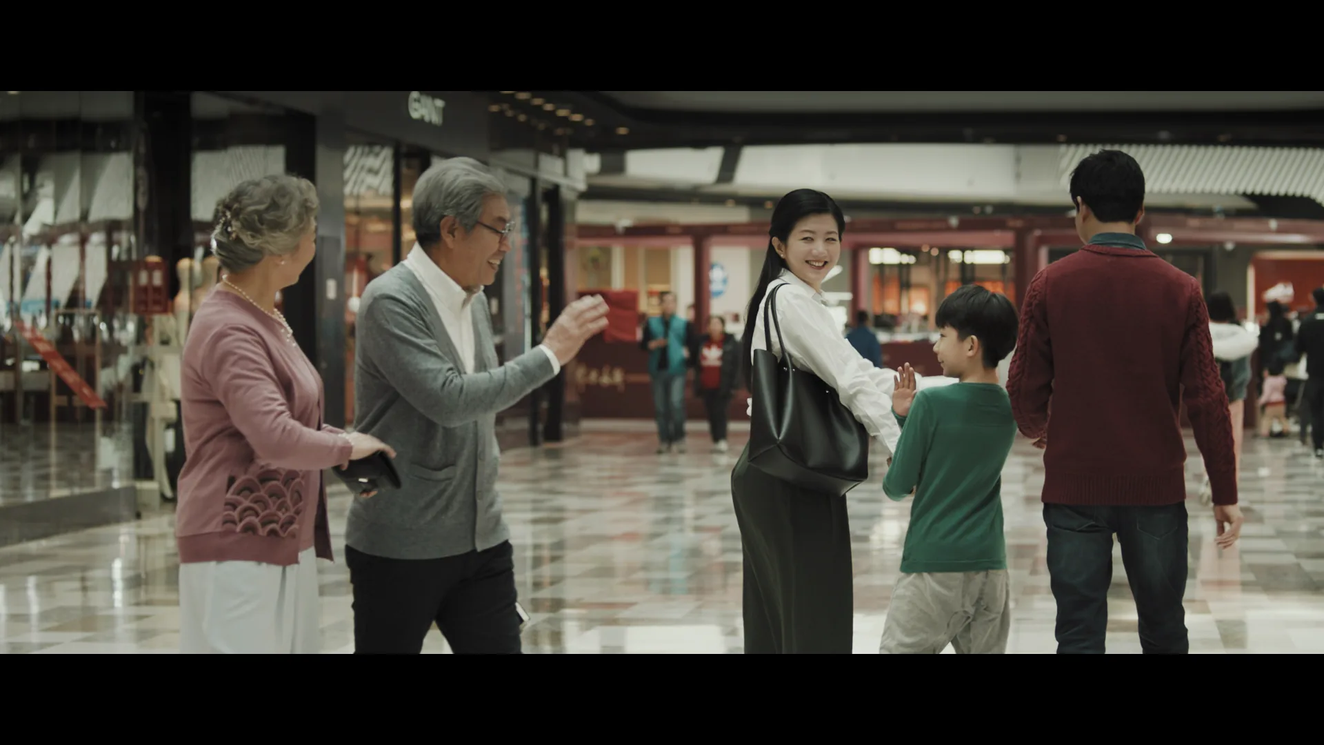 Grandparents, parents and the boy walking together through a Wanda mall