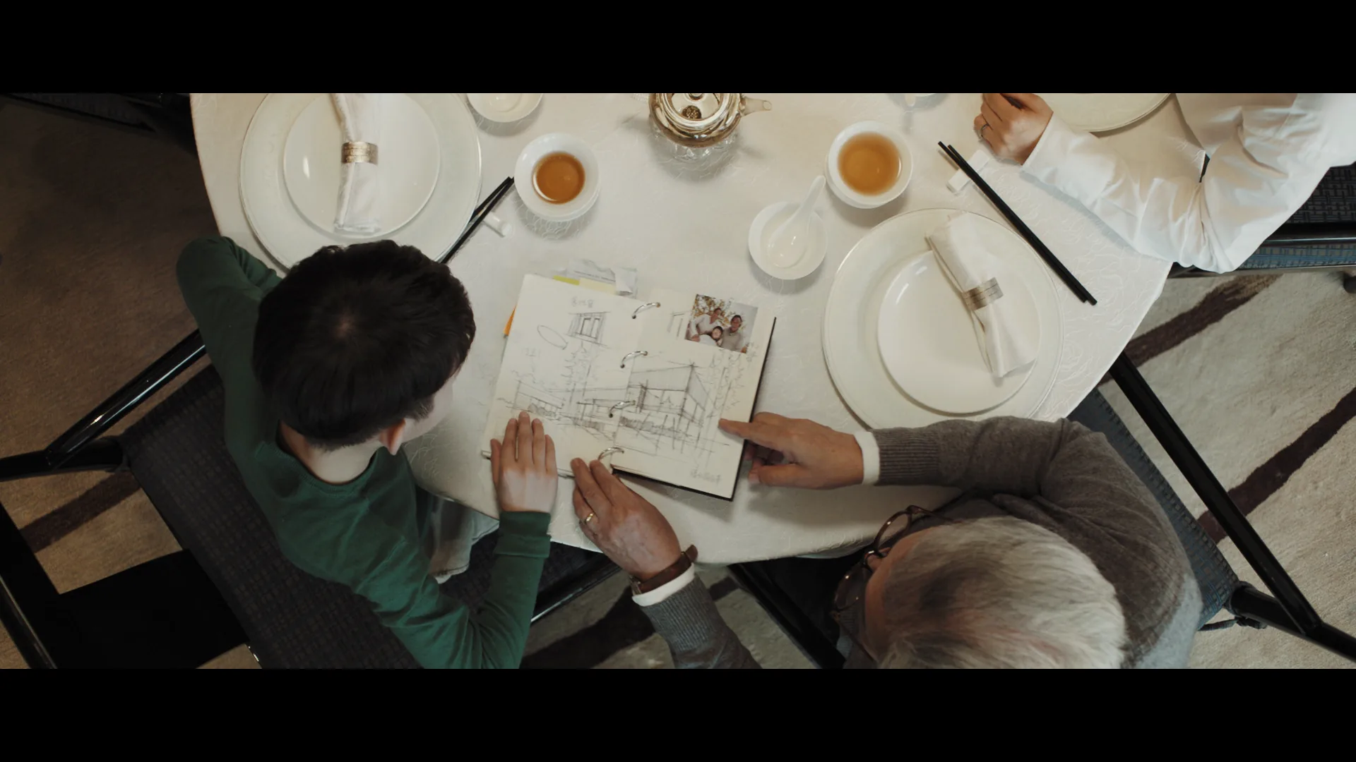 Overhead view of the grandfather and boy looking at architectural drawings and a family photograph