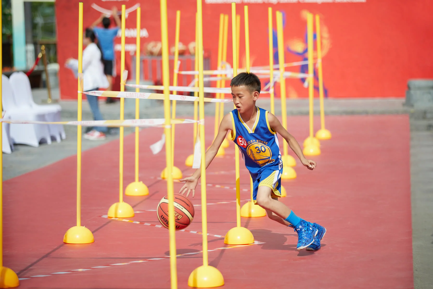 A young player dribbles through an outdoor basketball skills course