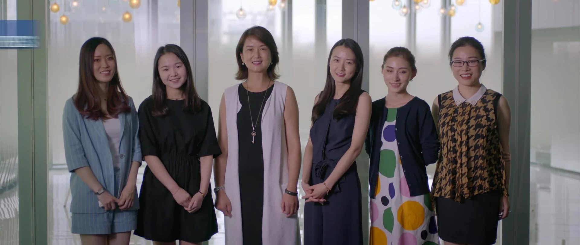 Six employees standing together in an office setting.