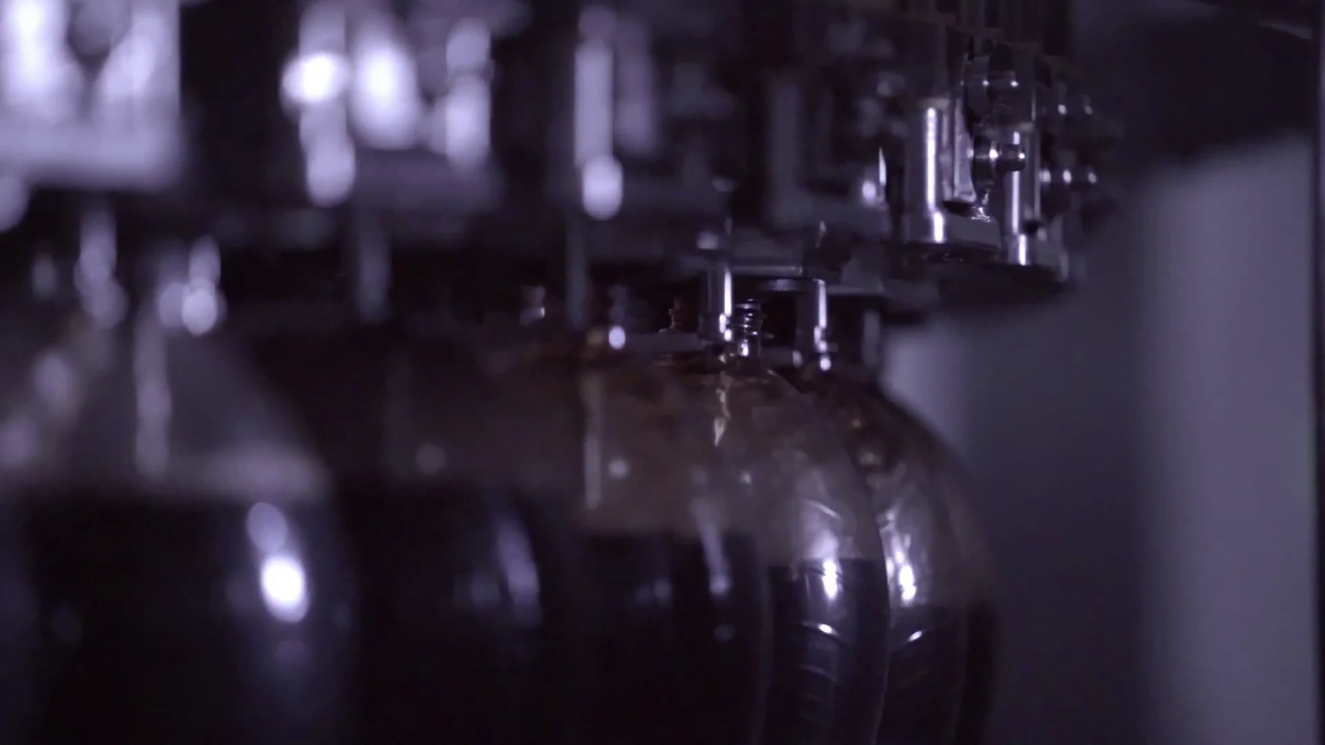 A close view of bottles beneath the filling equipment.