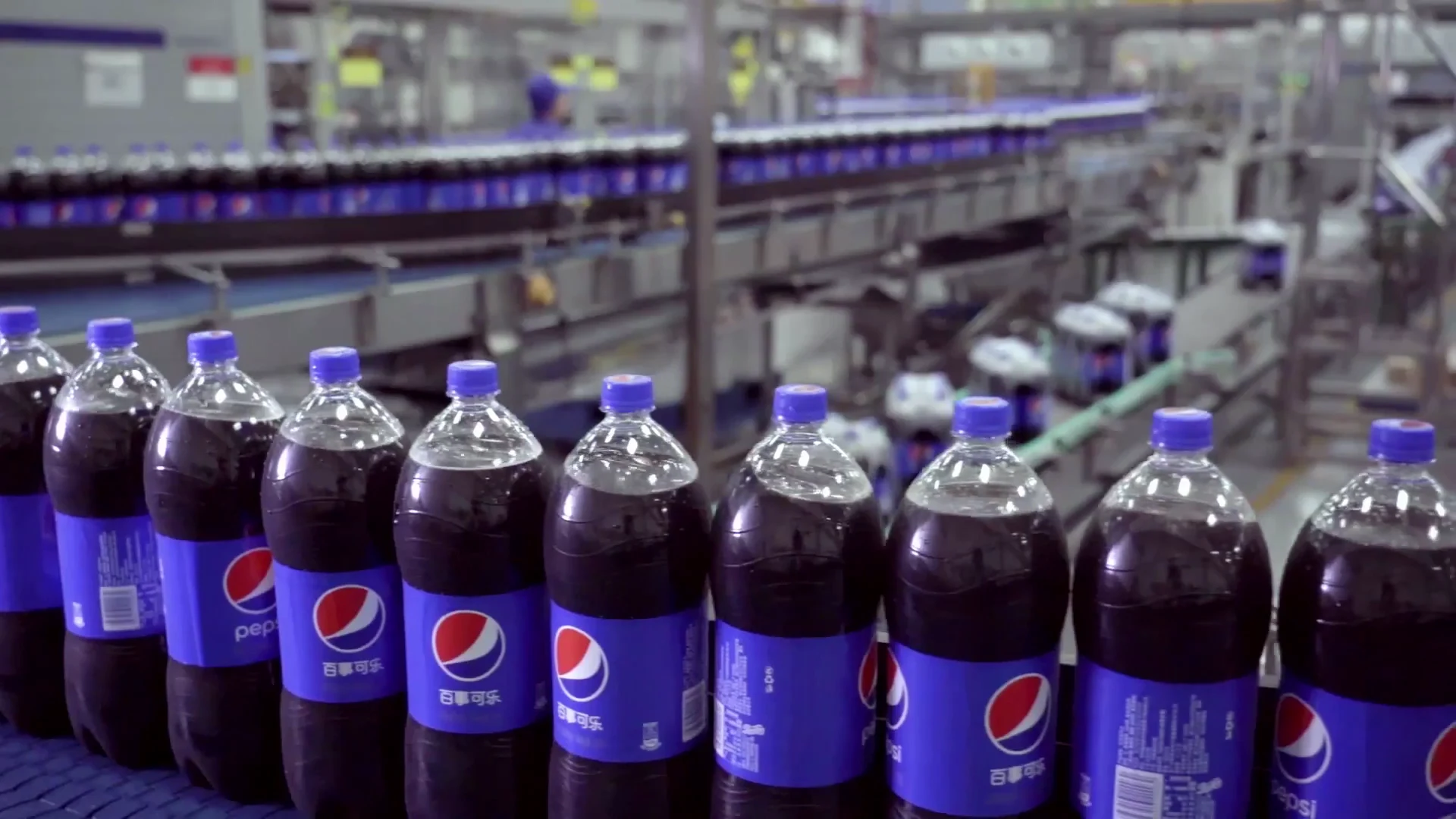 Rows of finished Pepsi bottles on conveyors across the factory floor.