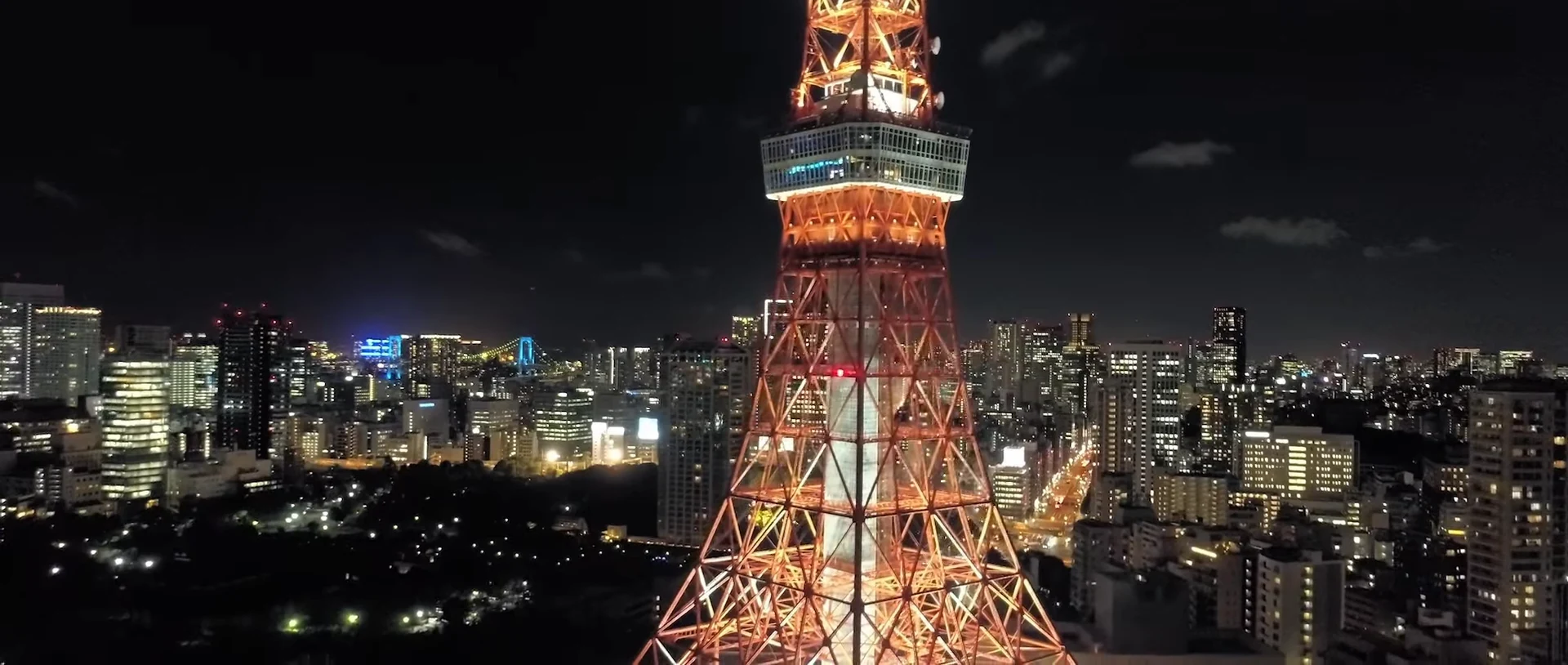 An orange-lit lattice tower above the city at night.