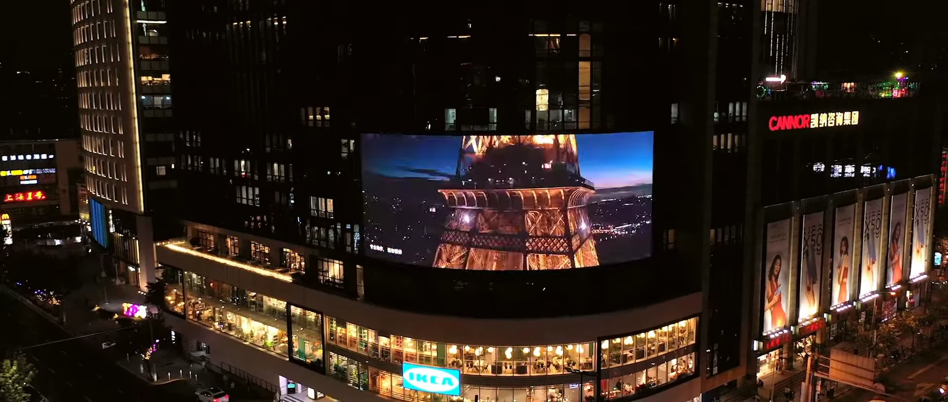 The Eiffel Tower appears on the Shanghai screen above the illuminated streets.