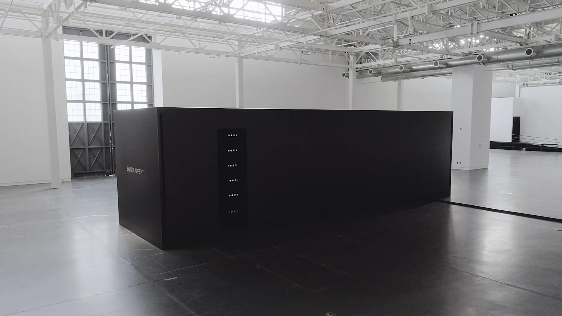 The black screen installation within the white museum hall.