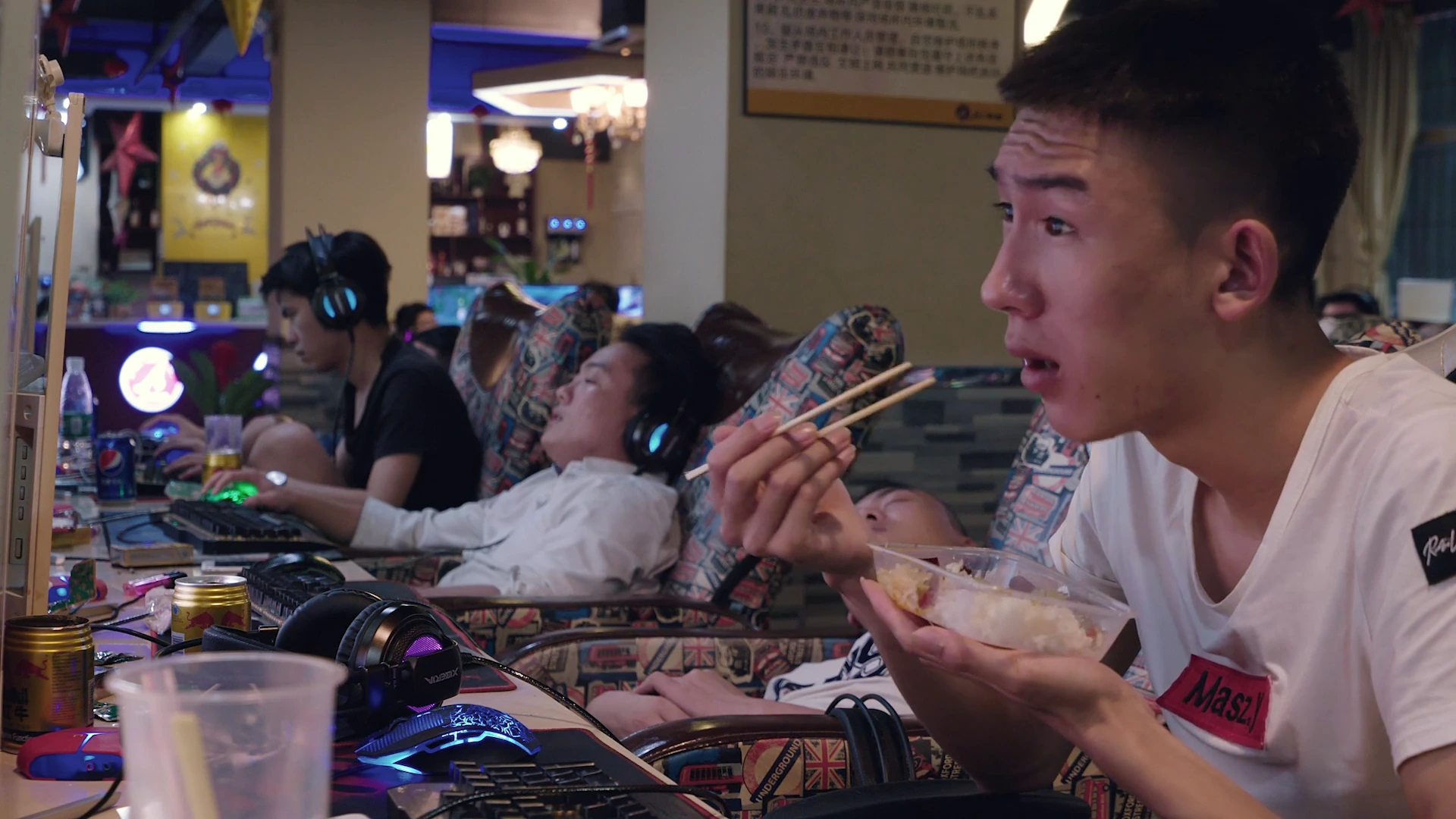 People eating, resting and using computers in an internet café. Frame from Ascension.