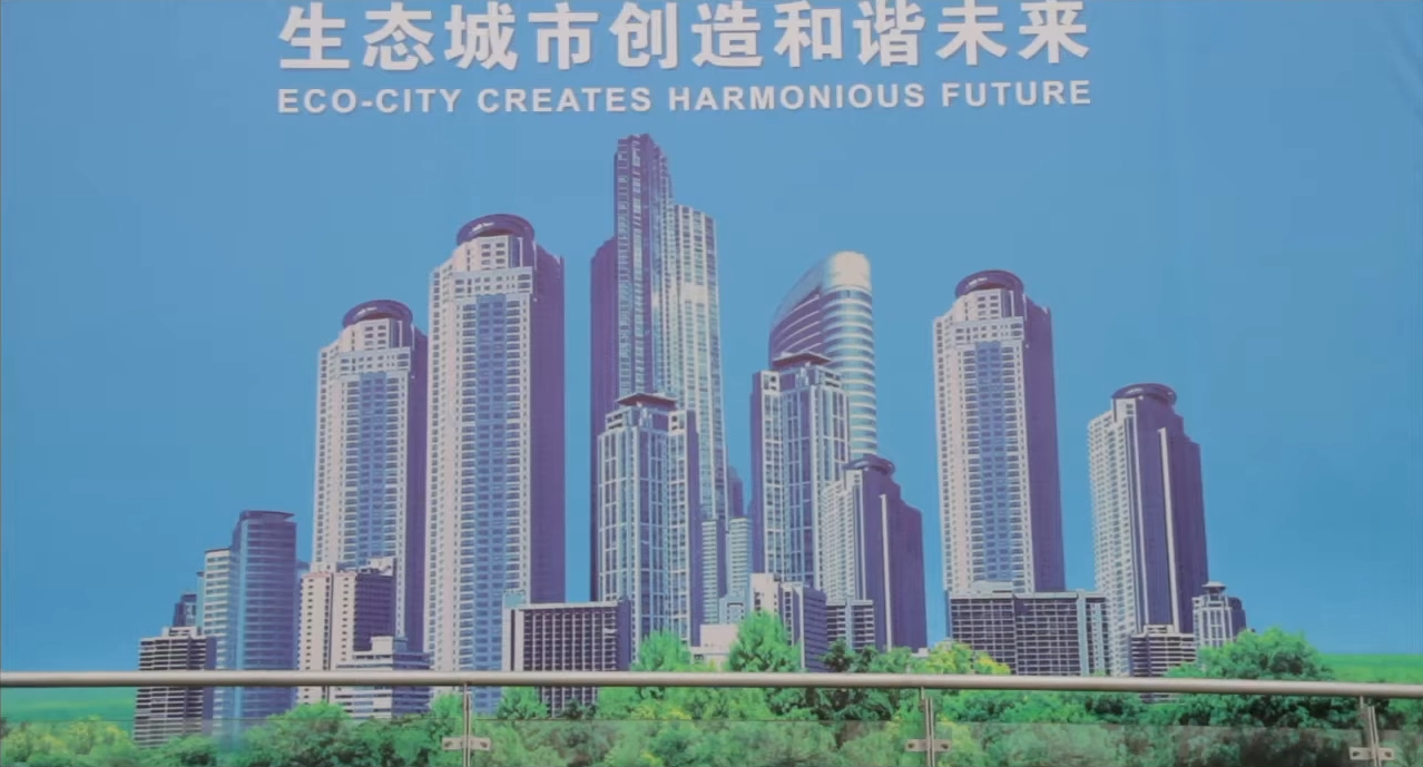 An illustrated vision of an eco-city on a roadside billboard. Film still.