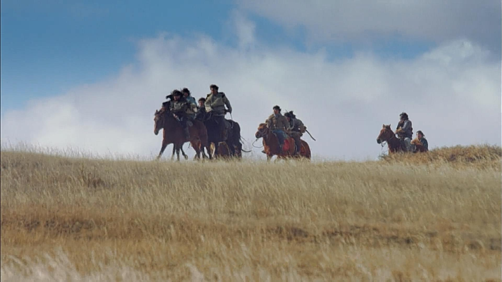 Mounted riders crossing open country in a historical re-enactment.